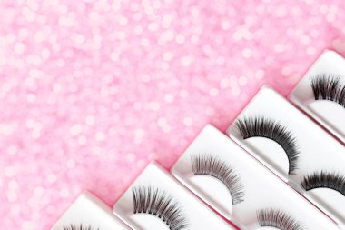 Pembe arka planda farklı sahte kirpikleri var. Güzellik deseni. Makyaj araçları. 