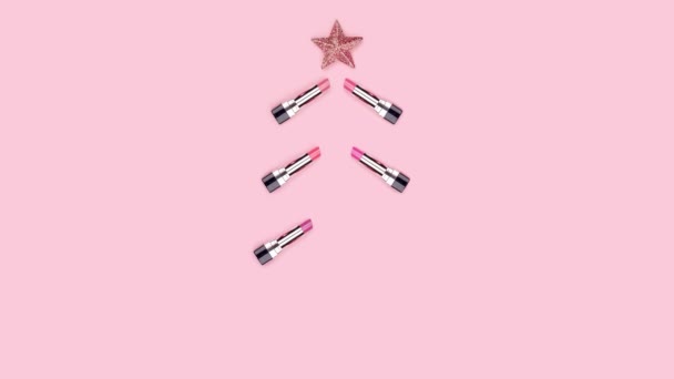 圣诞树由彩色口红、圣诞球、粉色背景的星星组成。美丽的圣诞概念。化妆配饰。化妆品。红色，紫色的石碑，唇彩。停止动作动画. — 图库视频影像