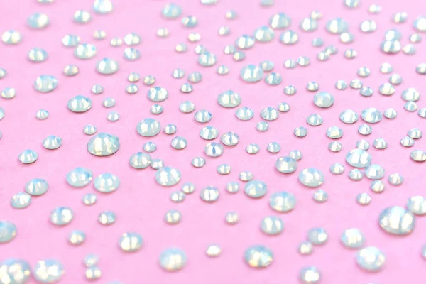 Diamanti, strass su sfondo rosa pastello. Bellissimo sfondo festivo. Cristalli per nail art, trucco e design — Foto Stock