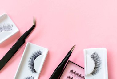 Pastel pembe arka planda kirpik uzantısı için araçlar. Sahte kirpikler ve cımbızlar. Güzellik salonu. Makyaj kozmetikleri. 