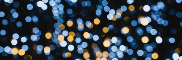 Noel ışıkları. Yeni yıl kutlamaları mavi, altın ve siyah arkaplanı bulanıklaştırdı. Güzel zemin, doku. Bokeh. Xmas.