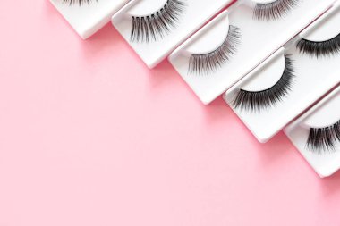 Pembe renkli modaya uygun arka planda farklı takma kirpikleri var. Güzellik deseni. Makyaj malzemeleri. Kozmetik ürünleri.