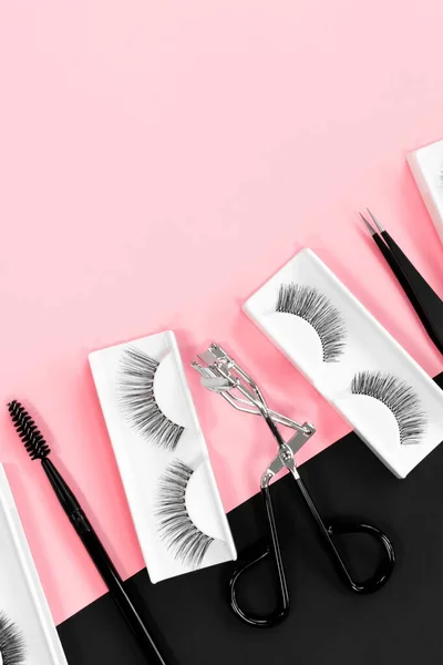 Fake eyelashes. Makeup accessories. Cosmetics. Tools for eye lash extensions on pink and black background. Vertical. 스톡 사진