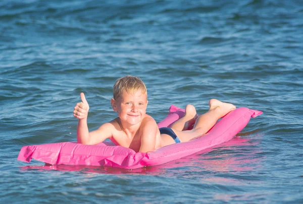 Klein kind zwemmen in de zee op opblaasbare matras — Stockfoto