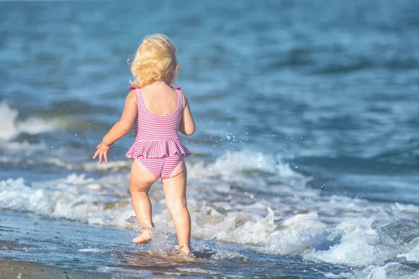 Beetje meisje spelen met golven — Stockfoto