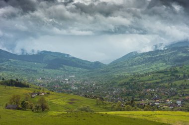 Dağ köyü üzerinde alçak dramatik bulutlar. Ukrayna Karpatları.