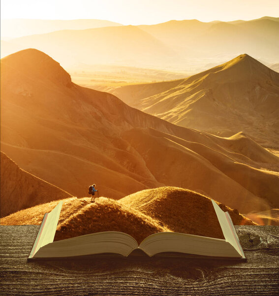 Girl hiker with backpack and trekking sticks standing on the pages of an open book. Travel and education concept.