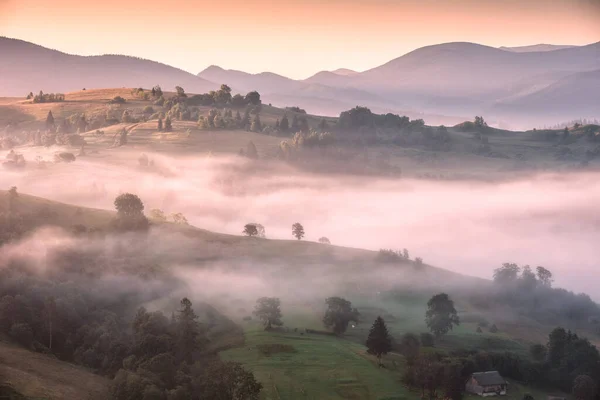 stock image Majestic view of alpine village covered with fog in a light of golden sunrise. Early morning scene, beauty misty image, fantastic landscape. Carpathians, Ukraine.