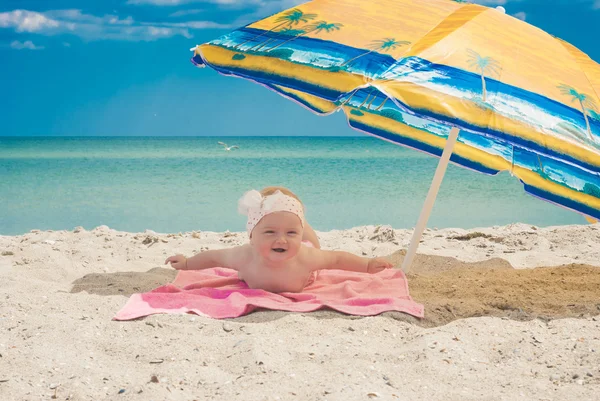 Baby op een strand onder de paraplu — Stockfoto