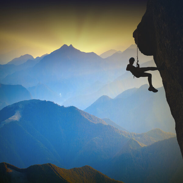 Climber on a cliff against misty mountains