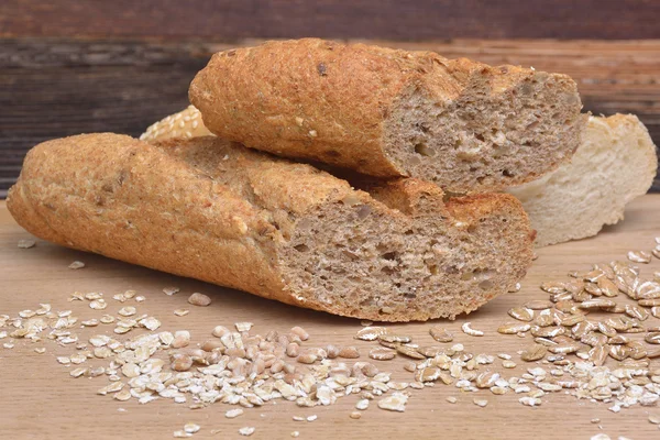 Brot und Körner auf Holzgrund — Stockfoto