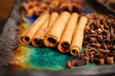 Seramik tabakta baharatlar: tarçın çubukları ve karanfiller