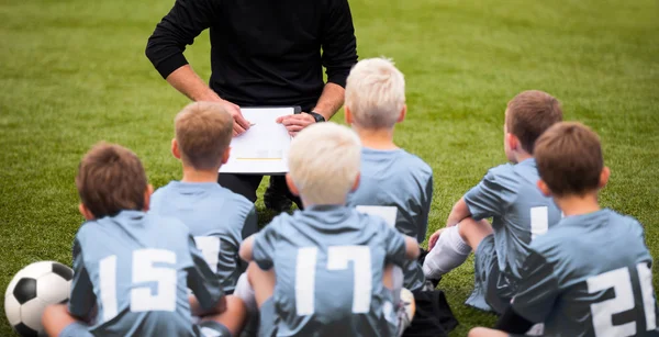 प्रशिक्षक प्रोत्साहन देणारी मुले फुटबॉल टीम. स्टेडियममध्ये कोचसह फुटबॉल संघ. युवा फुटबॉल संघाचा प्रशिक्षक. मुले कोचच्या सूचना ऐकतात. प्रशिक्षक देणे टीम बोलणे — स्टॉक फोटो, इमेज