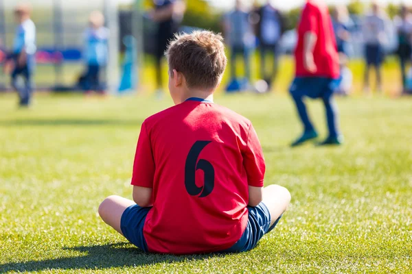 スポーツ フィールドの上に座って若いサッカー選手. — ストック写真