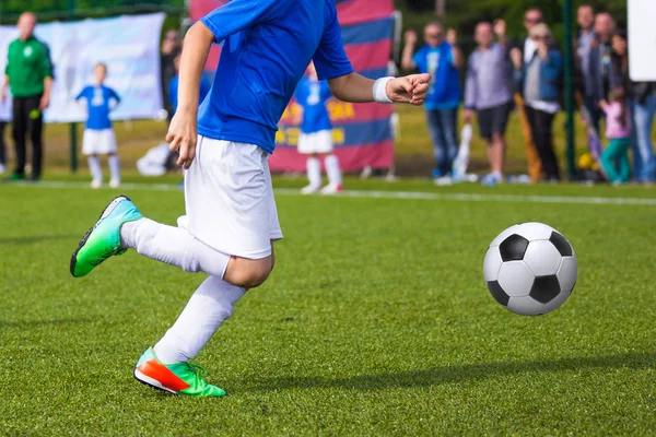 Jovem jogador de futebol chutando bola em esportes roupa azul — Fotografia de Stock