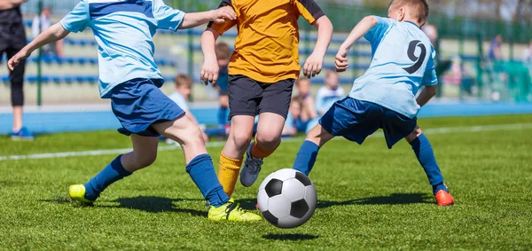 Des jeunes garçons donnent des coups de pied au football sur le terrain de sport . — Photo