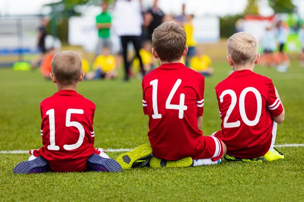 Niños jóvenes en el equipo de fútbol sentados juntos en el campo de deportes . —  Fotos de Stock