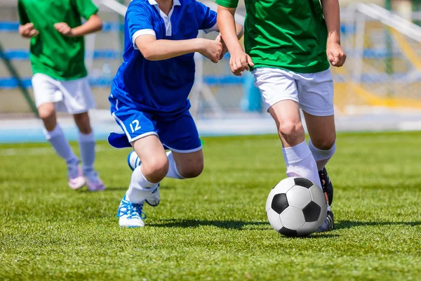 少年スポーツのフィールドでサッカーを蹴るします。青と緑の青年チームの大会に出場 — ストック写真