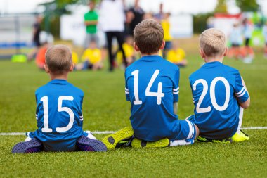 Gençlik futbol futbol takımı birlikte alanında oturup ve futbol maçı izlerken. Yedek oyuncular takım destekleyen bankta olarak genç erkek