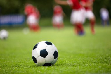 Futbol sahasında futbol topu. Green Grass Futbol Sahası. Futbol sahaları ve oyuncuları, futbolcular arka planda antrenman yapıyor.