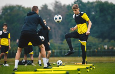 Genç Futbolcular Genç Koçla Eğitim Oturumunda. Gençler için Futbol Kampı. Antrenman Biriminde Tekmeleyen Çocuk. Beyazlar Futbol Yeteneklerini Geliştiriyor