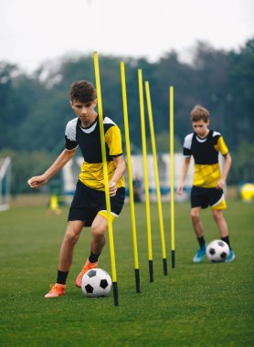 Slalom 'da koşan ve Polonyalılar arasında top süren genç futbolcular. Gençler için Futbol Antrenmanı. Genç Seviye Futbol Takımı Eğitim Birimi