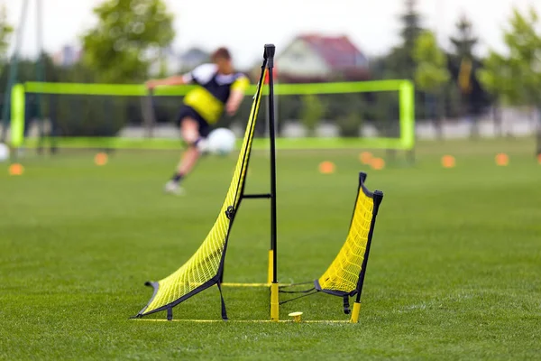 Soccer Training Goal. Sports Training Aid Equipment. Soccer Trainer Rebound Net Football. Sports Practice Tools. Soccer Player Kicking Ball on Training in the Background