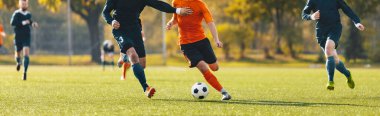 Bir turnuva maçında futbolcuların düelloda oynadığı yatay görüntü. Futbolcu defans oyuncusuyla yarışıyor. İsimsiz futbol oyuncuları lig maçını tekmeliyor