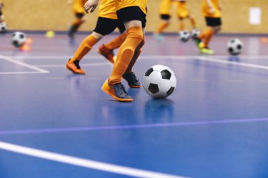 Gençlik takımı için kapalı alanda futbol antrenmanı. Tahta parke üzerinde koşan futbol topları olan genç çocuklar. Kapalı futbol okulu antrenmanı. Futbol takımındaki çocuklar.