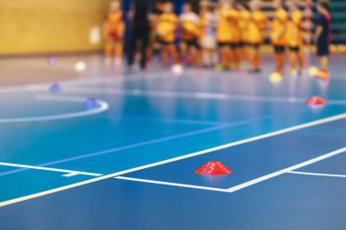 Kapalı Futbol Dersi. Beden Eğitiminde Çocuklar ve Öğretmen Geçmişi Bulanık. Tahta Saha Sahasında Futbol Eğitim Konisi İşaretleyici