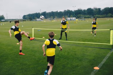 Gençlik futbol kulübündeki genç çocuklar futbol tenis antrenmanı yapıyorlar. Genç futbolcular antrenmanlarda futbol oynuyorlar. Gençler çim sahada futbol çalışıyor.. 