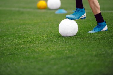 Futbolcu ve top. Antrenman sahasındaki futbolcu. Top çimlerin üzerinde duran futbolcunun görüntüsünü kapat