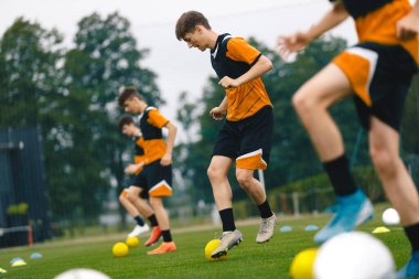 Antrenmandaki futbol oyuncuları. Genç erkekler küçük toplarla antrenman yapıyor. Genç Çocuklar için Futbol Yaz Kampı. Antrenmandaki Futbol Oyuncuları 'nız kutlu olsun. Gençlik Takımı Turf Pitch 'te Topları Tekmeliyor