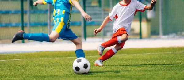 Two Soccer Boys Kicking Ball in Opposite Teams. Football Duel; Kicking Ball Moment. Young Football Players Running in Duel and Playing Soccer Tournament Match. Sports Competition for Youth Athletes