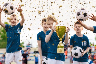 Futbol Takımı Kutlaması. Neşeli Çocuklar Futbol Turnuvasında Başarı Kutlaması. Genç Spor Takımı Konfeti Kutlamasında Yükselen Altın Kupa. Zıplayan ve neşeyle top atan çocuklar.