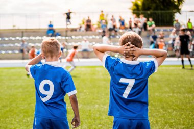 Futbol Maçındaki Spor Çocukları. Takımdaki çocuklar üzerinde mavi forma ve oyuncu numaraları olan tişörtler giyiyor.