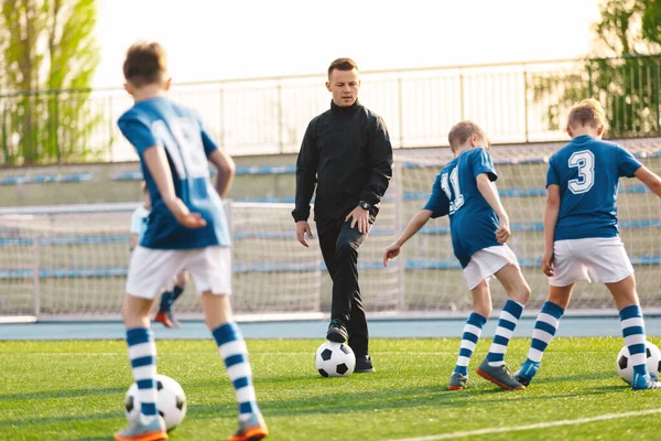 School Sports Teacher on Training with Children Team. Young Man Coaching Kids at Football Class