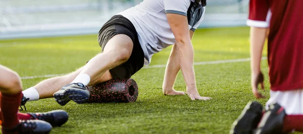 Futbol fizyoterapisti köpük silindir kullanan kişisel antrenör. Antrenör, futbol takımındaki çocuklara egzersiz gösteriyor. Okul takımında futbol esneme seansı