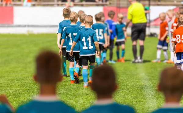 子供サッカー選手のグループが試合前にフィールド上を歩く 決勝トーナメントの前に2つのユースサッカーチームが並んでいる 赤と青のシャツチーム — ストック写真