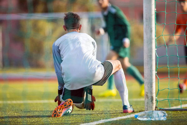 Adult Football Goalkeeper Player Catching Ball in a Goal. Soccer Player in a Game. Goalie in Action. Goalkeeper in Soccer Uniform and Gloves