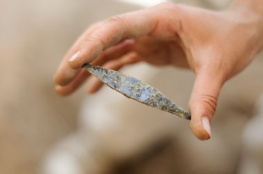 obsidian arrowhead isolated on archaeologic background clipart