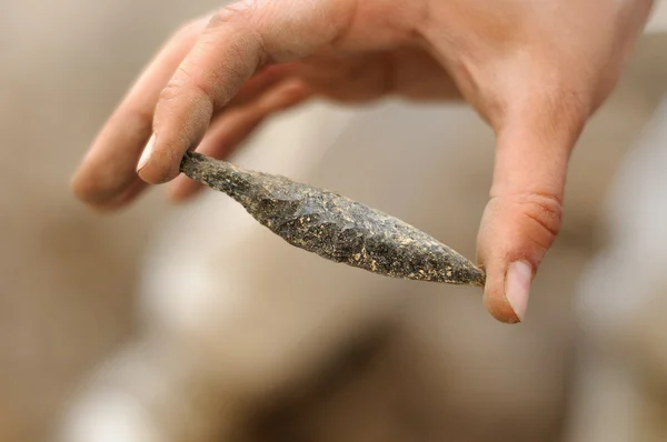 Obsidian arrowhead isolated on archaeologic background — Stock Photo, Image