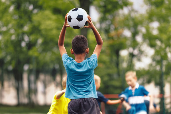 Child Throwing Soccer Ball During Football Practice; Kids Team Training and Outdoor Youth Sports Activity