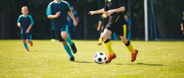 Gençler Futbol Oyunu; Çocuklar Yeşil Sahada Futbol Maçı sırasında Topla Koşuyorlar