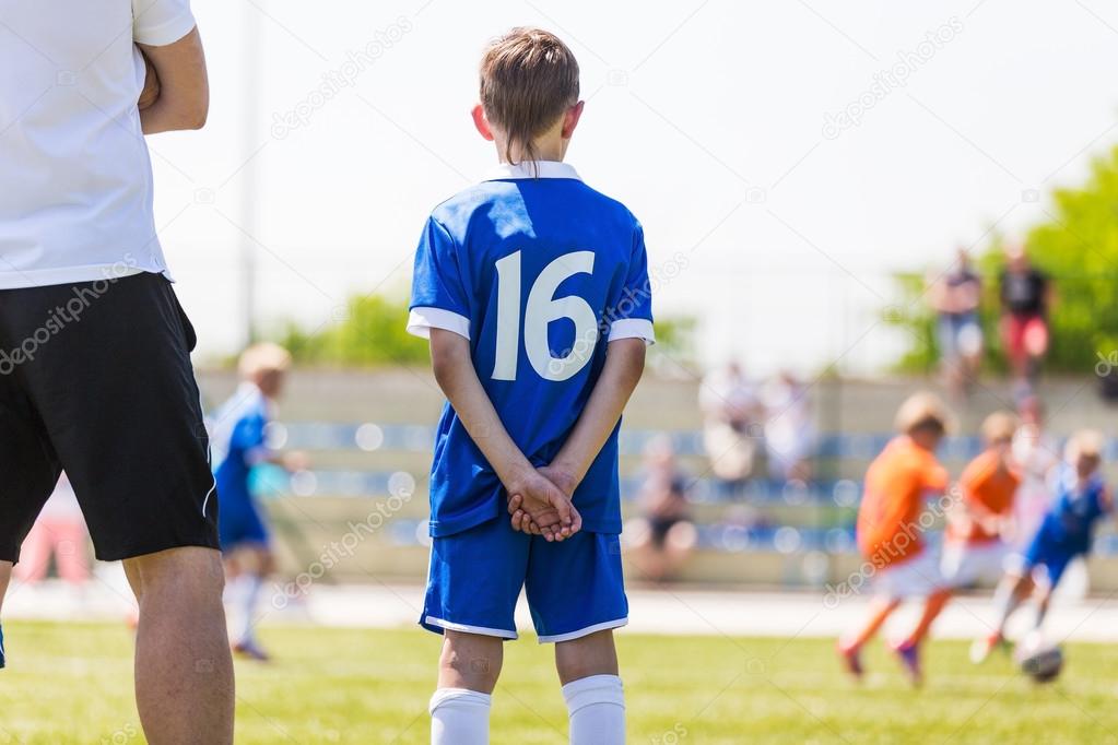 Coach and soccer player watching football match.