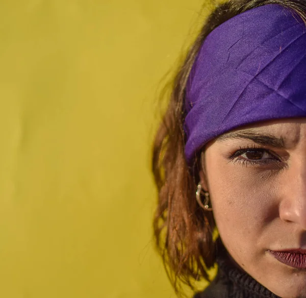 Sarı arka planda mor kurdeleli genç bir kadın kameraya bakıyor. Aşırı feminist kadın kavramı