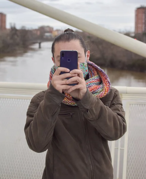 Adam fotoğraf çekmek için cep telefonunu kaldırıyor..