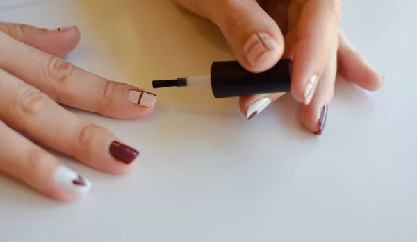 Kadınların elleri tırnak boyamak için fırçayı kullanır.
