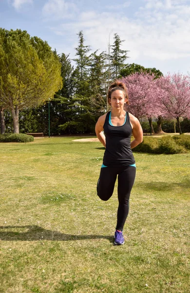 Sporcu kadın parkta bacaklarını esnetiyor..