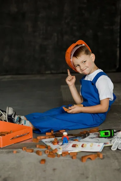 İnşaat kasklı ve tulumlu bir çocuk. Geleceğin inşaatçısı.